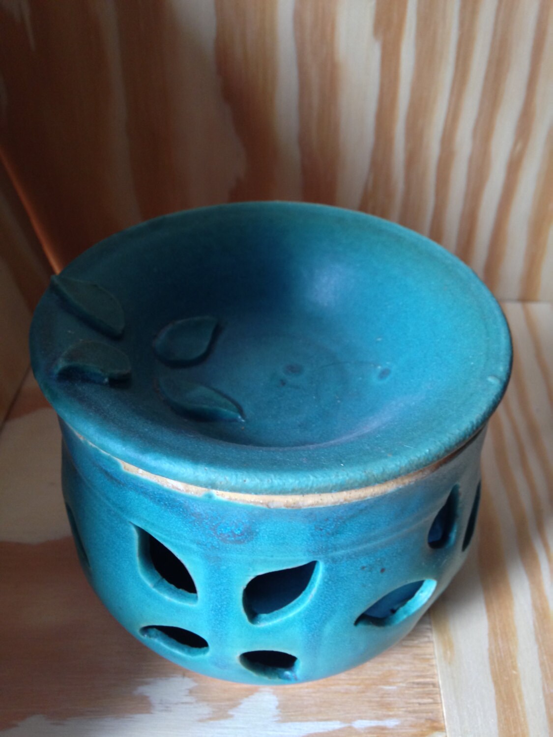 Teal melted wax warmer with hand cut out leaf pattern.