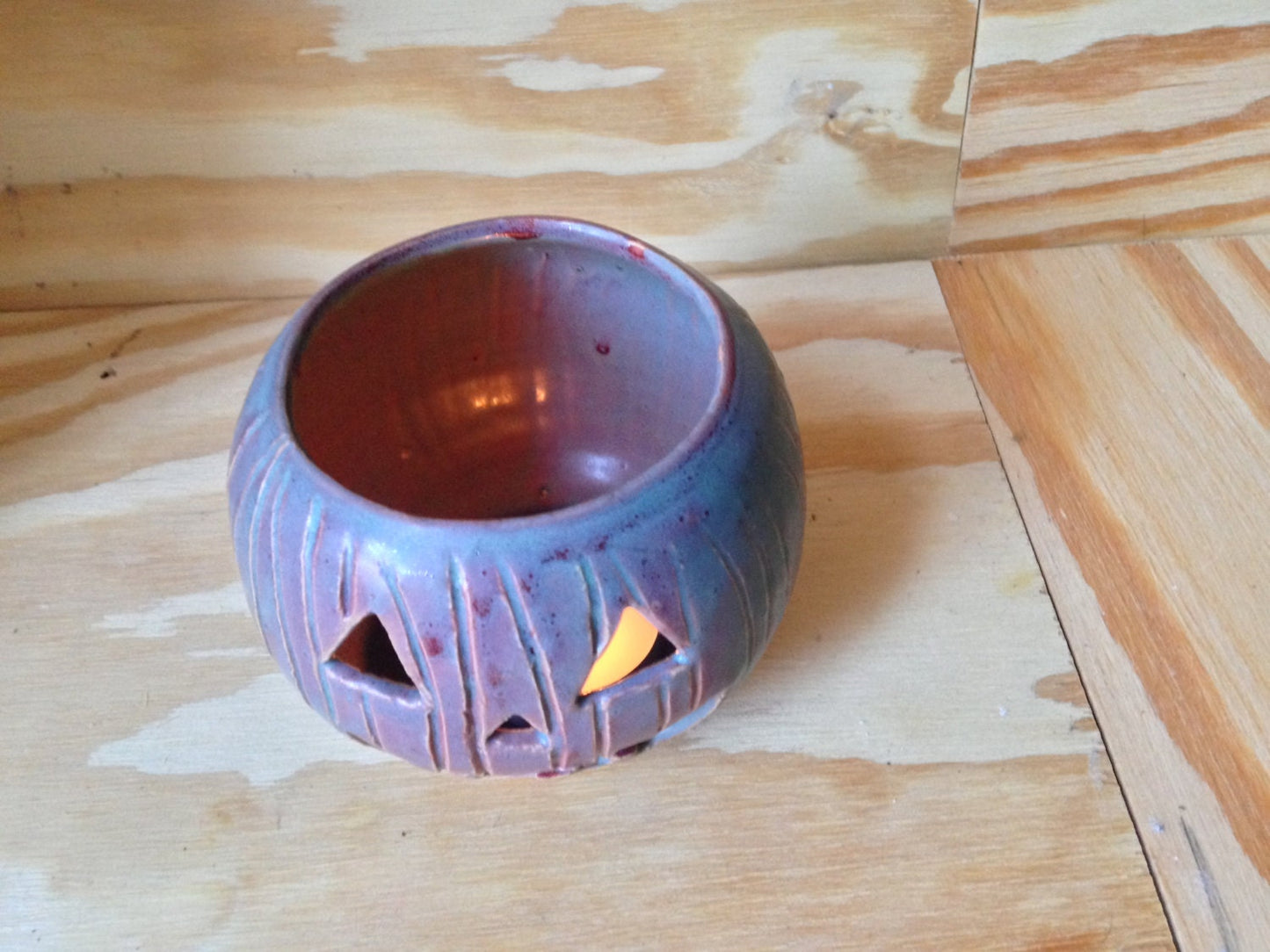 Green and red ceramic candle holder with carved pumpkin design