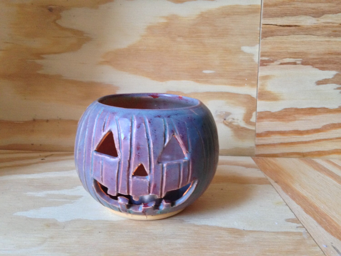 Green and red ceramic candle holder with carved pumpkin design