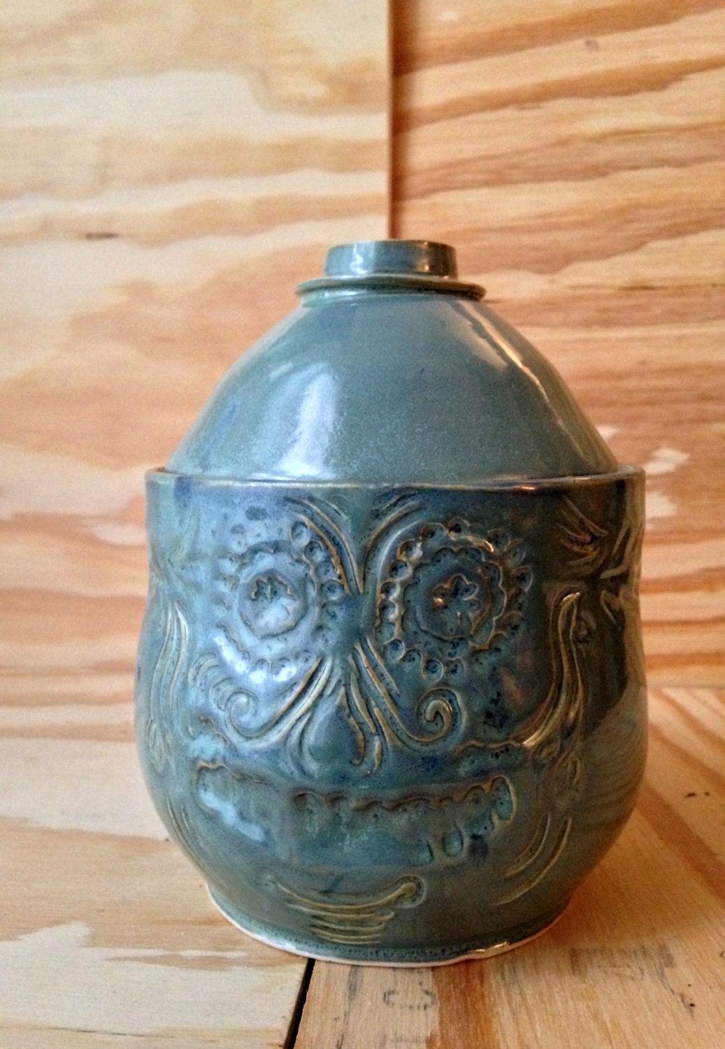 blue green medium sized lidded ceramic jar with free hand sugar skull carving