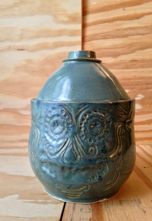 blue green medium sized lidded ceramic jar with free hand sugar skull carving