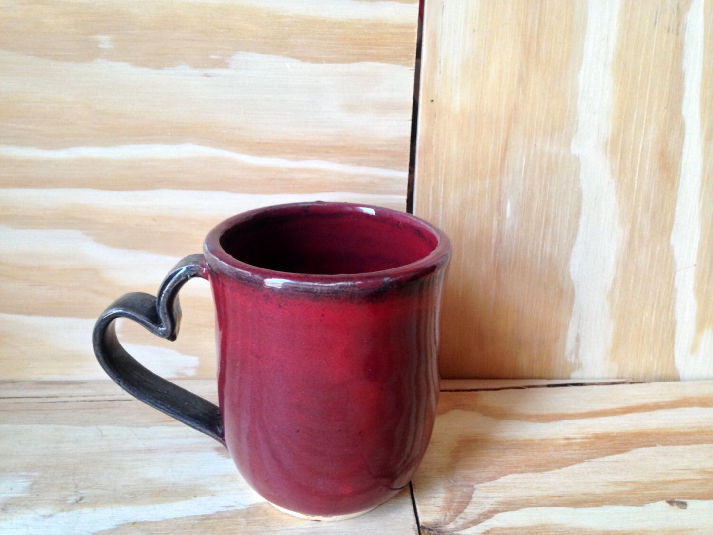 Handmade black and red ceramic coffee mug with heart shaped handle