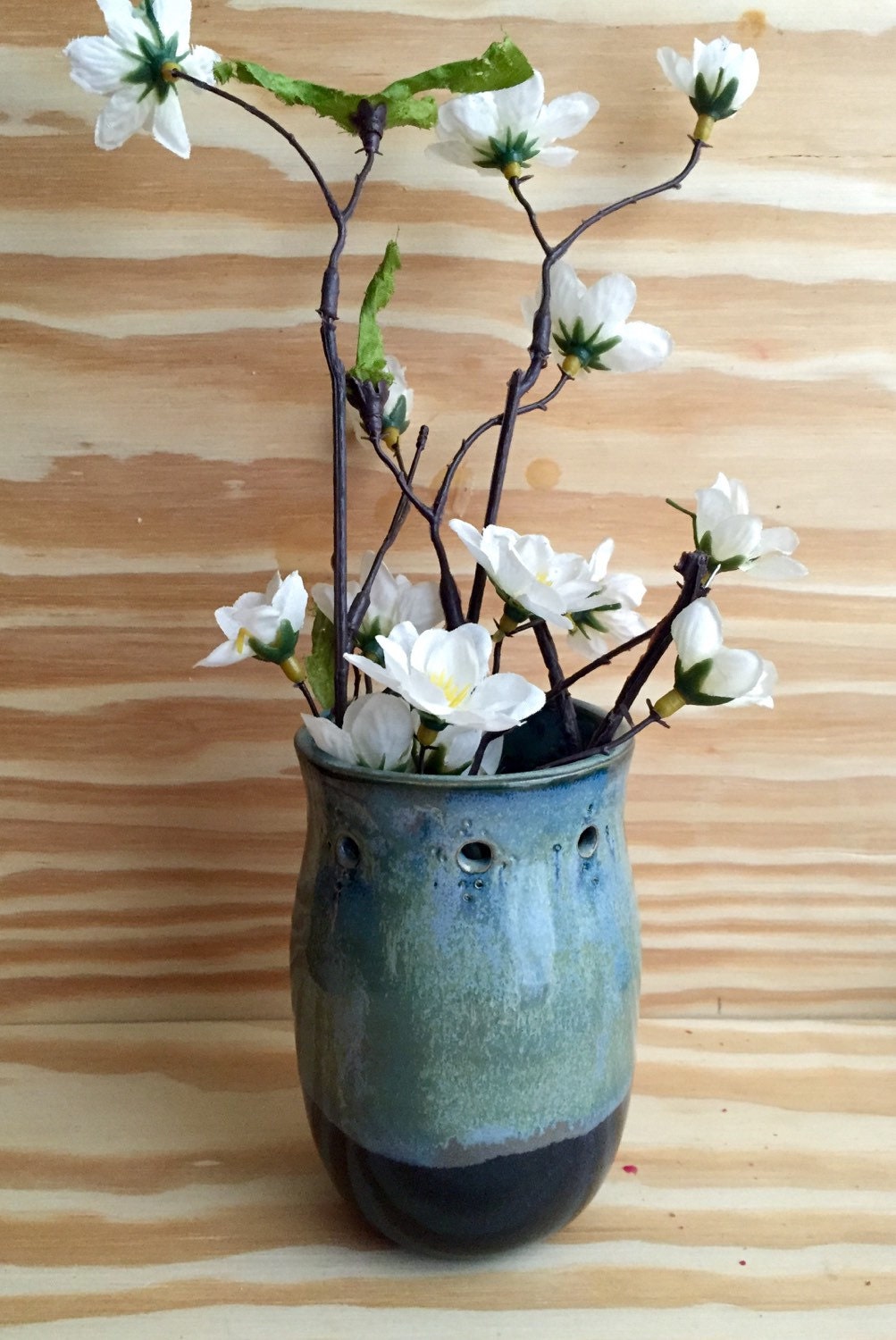 Handmade ceramic bud vase with flower cut out in shades of blue