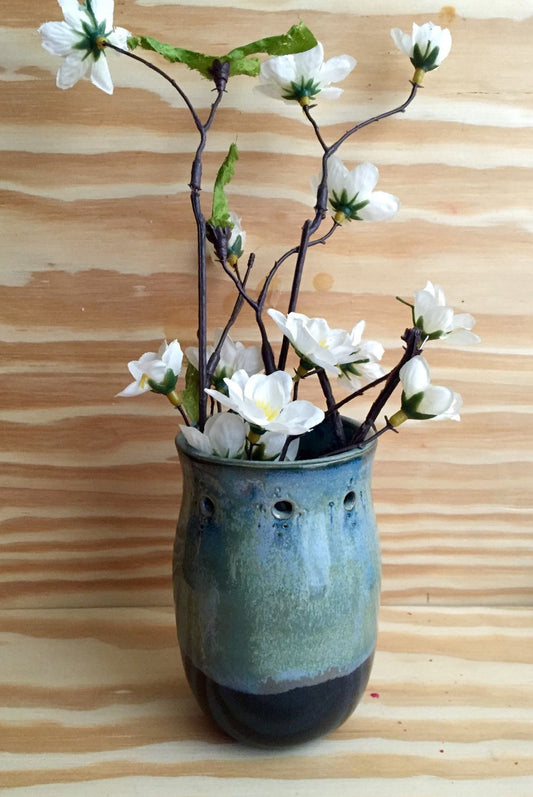 Handmade ceramic bud vase with flower cut out in shades of blue