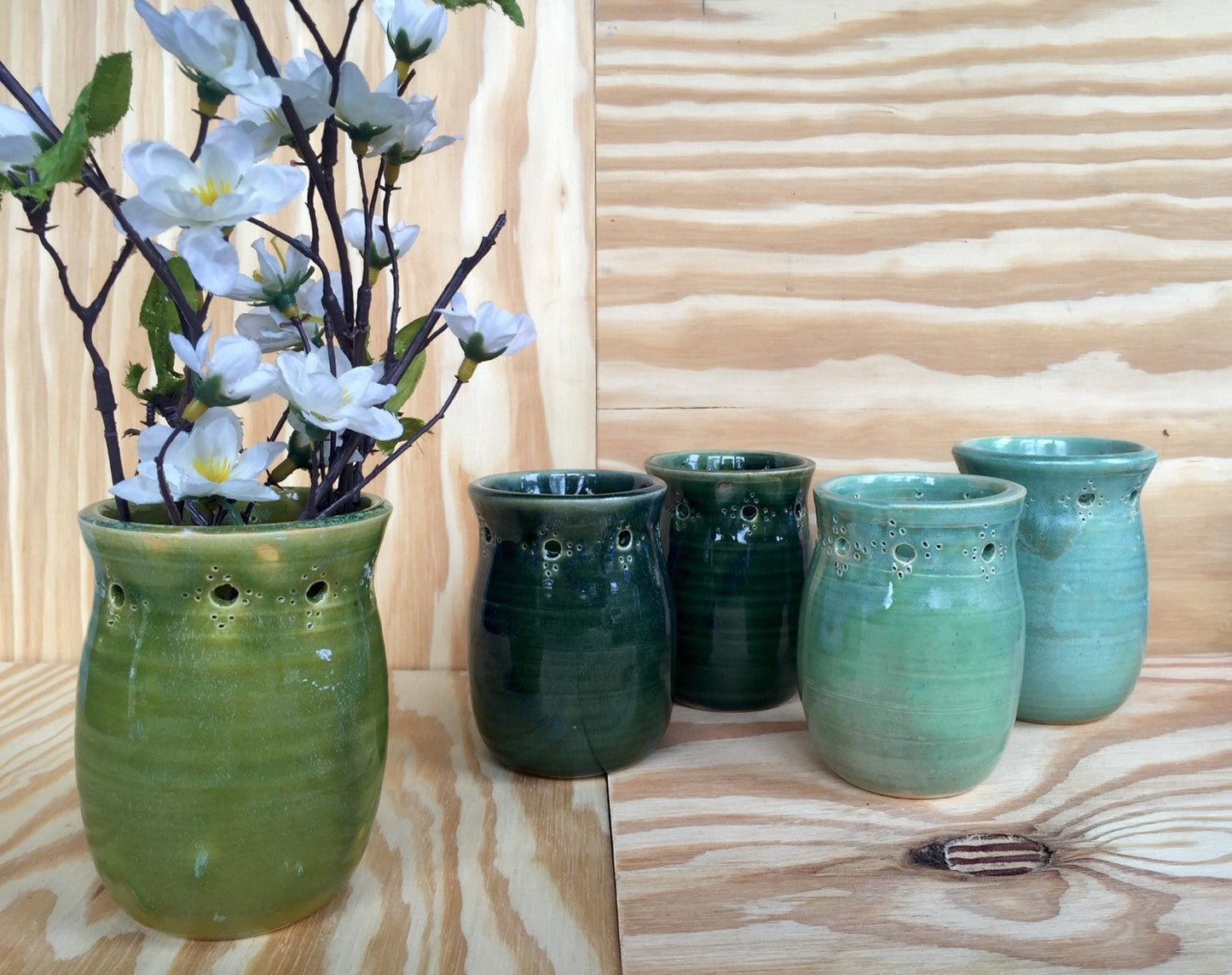 Handmade ceramic bud vase with flower cut out in deep green