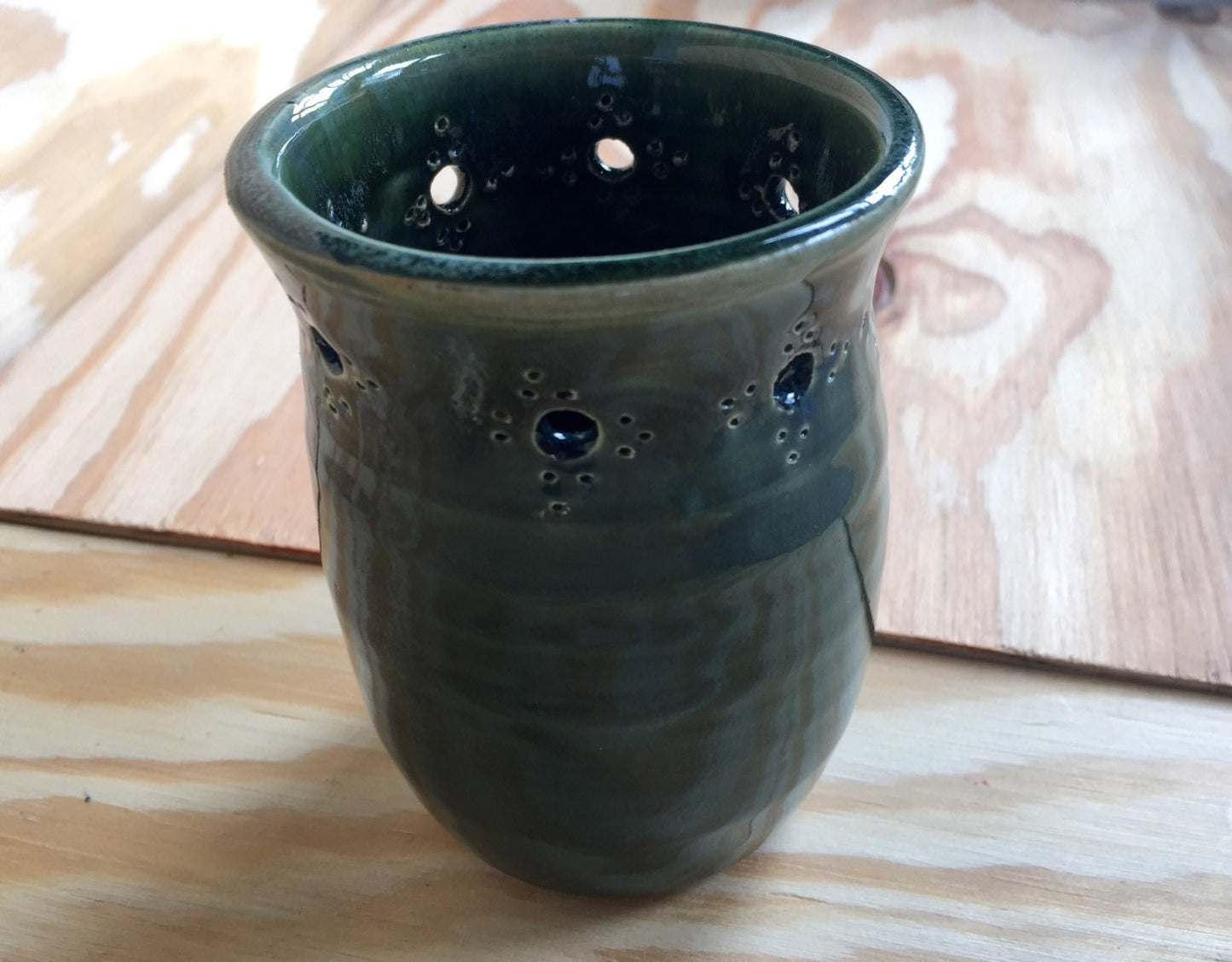 Handmade ceramic bud vase with flower cut out in deep green