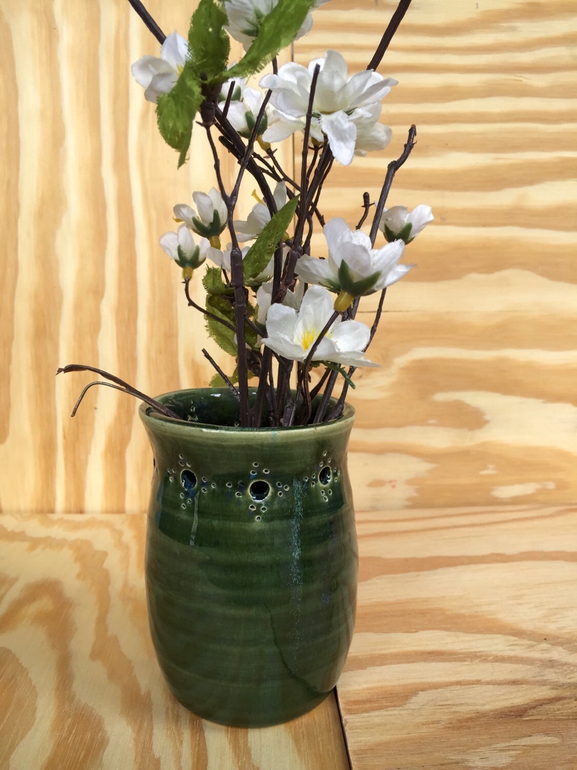 Handmade ceramic bud vase with flower cut out in deep green