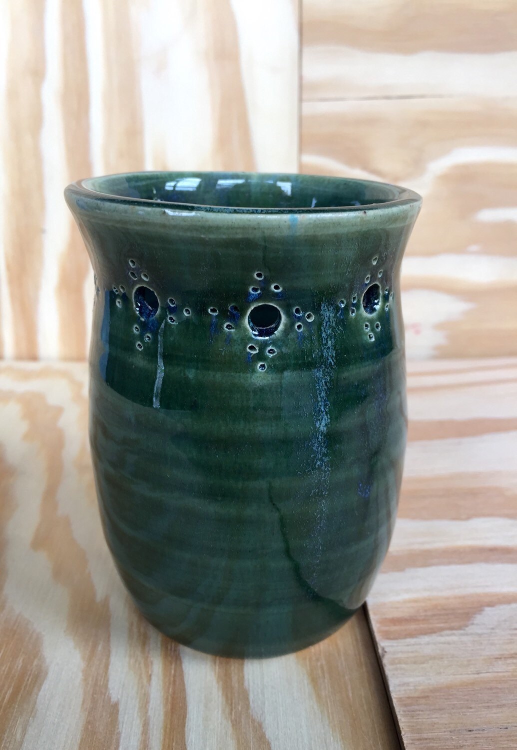 Handmade ceramic bud vase with flower cut out in deep green