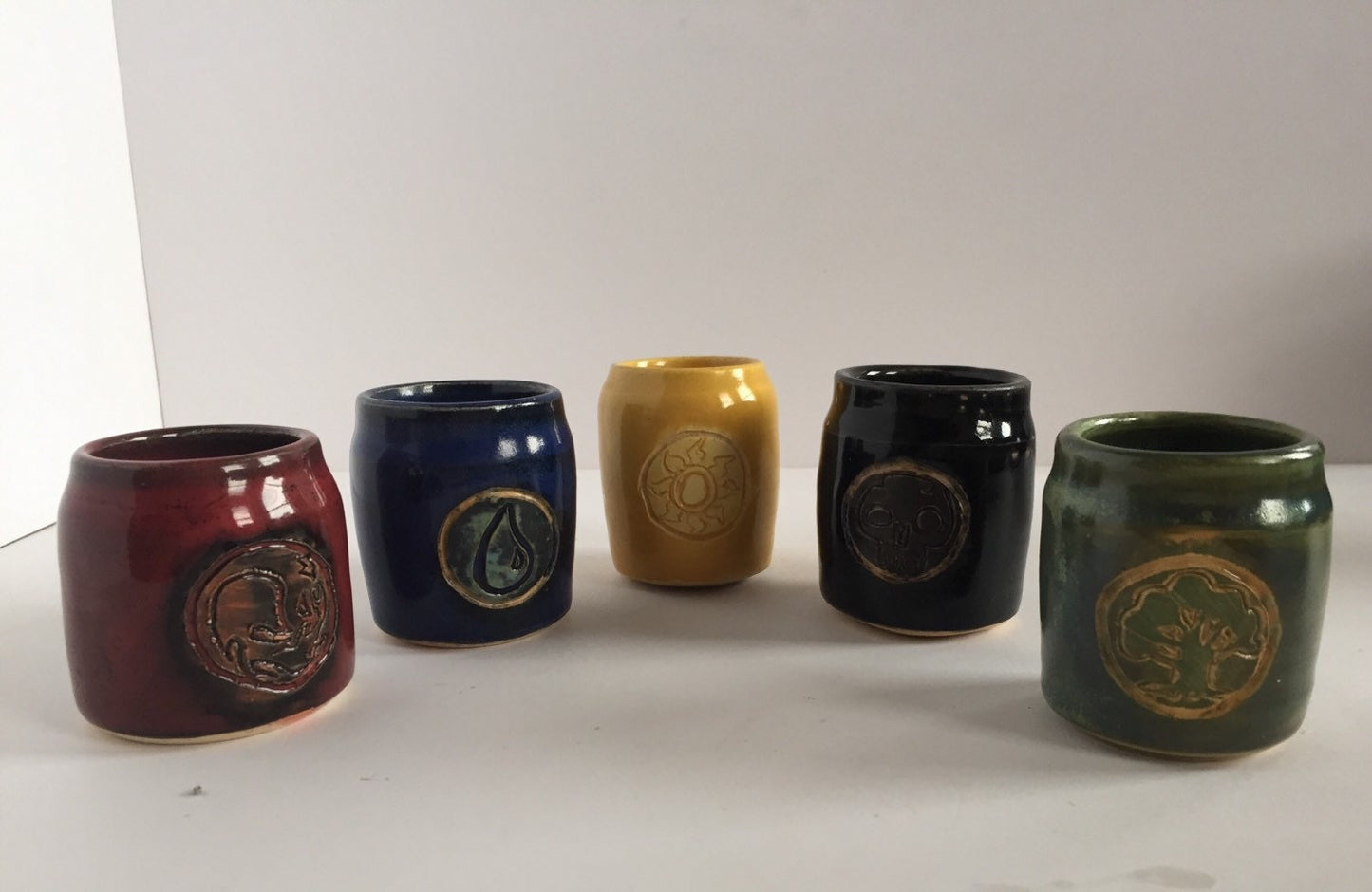 Handmade "magic the gathering" themed ceramic shot glasses with the five basic land