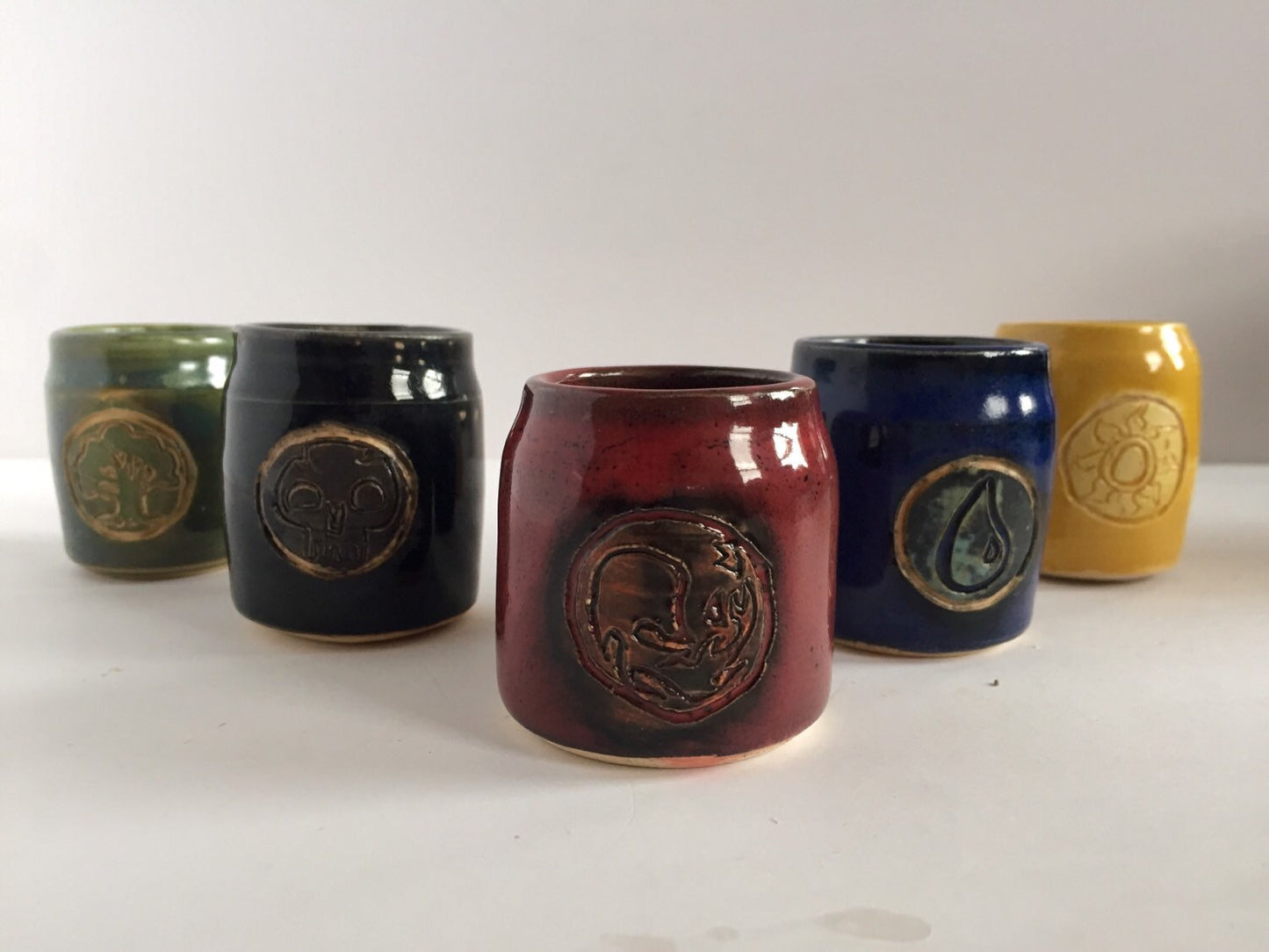 Handmade "magic the gathering" themed ceramic shot glasses with the five basic land