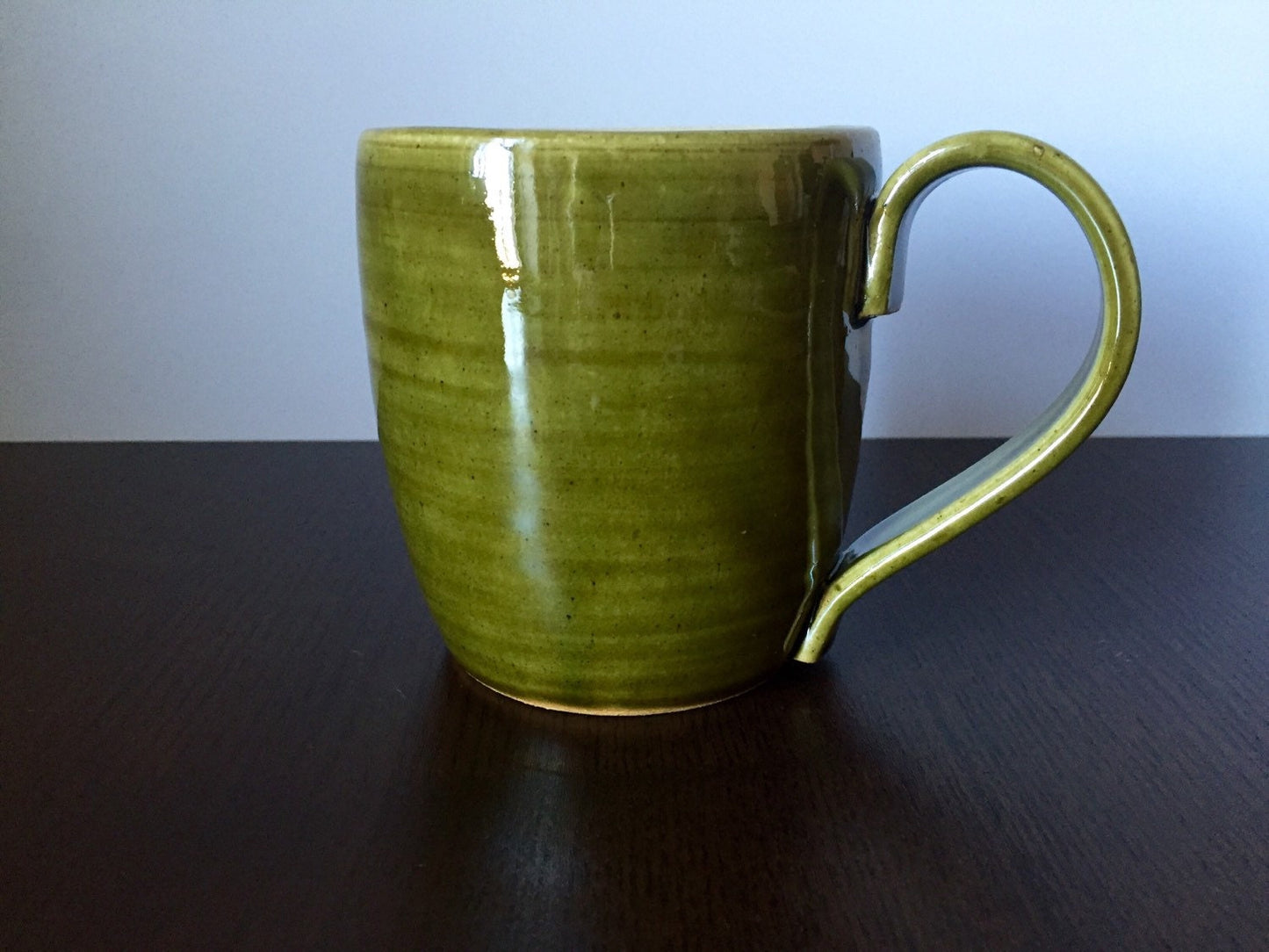 Ceramic coffee mug with  hikers symbol in green and white.